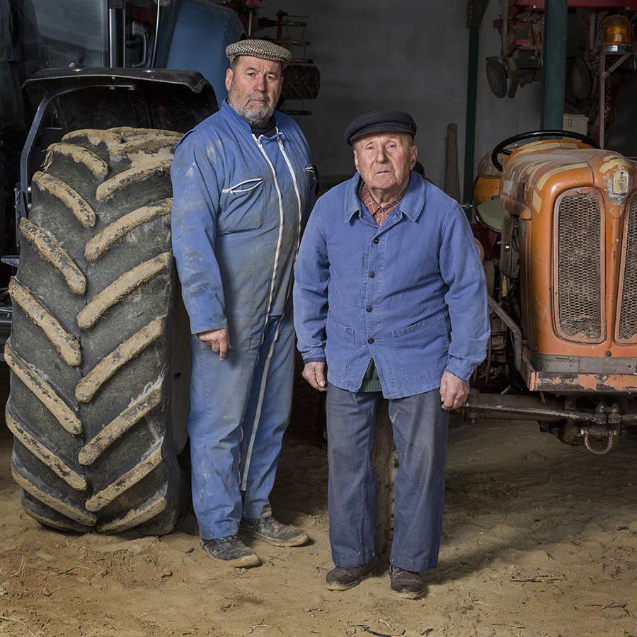 FRANCE - LA TERRE EN HERITAGE - (Transmission - Agriculture) Full-length portrait of a father and his son on the farm in front of their tractors. Portrait de plein pied d'un père et son fils à la ferme devant leurs tracteurs. FRANCE - LA TERRE EN HERITAGE TRANSMISSION AGRICULTURE pere; fils; paysan; transmission; agriculture; elevage; heritage; travail; campagne; crise; father; son; peasant; transmission; agriculture; breeding; heritage; job; campaign; crisis